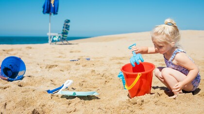 Menina brinca com areia na praia
