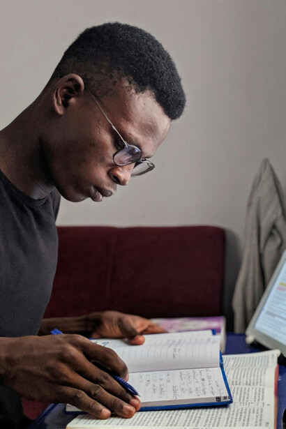Joven estudiando a partir de libros, notas y una computadora