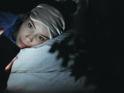 Mulher mexe em seu celular no momento de dormir. A cultura da produtividade excessiva, aliada à tecnologia que nos mantém conectados 24 horas por dia, tem levado muitas pessoas a sacrificarem horas preciosas de descanso em nome de metas profissionais ou acadêmicas. O resultado? Uma epidemia de privação de sono, com impactos devastadores na saúde mental e no rendimento