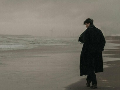A man walking by the sea alone beneath a dark sky, symbolising the ache of broken connections