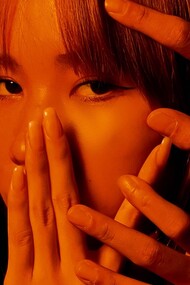 Young girl sadly gazes into the distance as her face is covered by hands