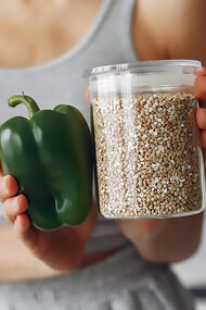 A woman prepares sustainable protein and fresh vegetables in kitchen