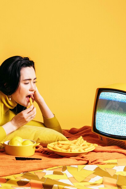 Woman mindlessly snacking and watching tv