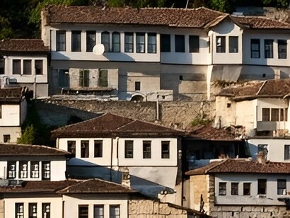 Traditional houses with rows of dark-framed windows climbing the hillside, representing the distinctive architecture of Berat, Albania