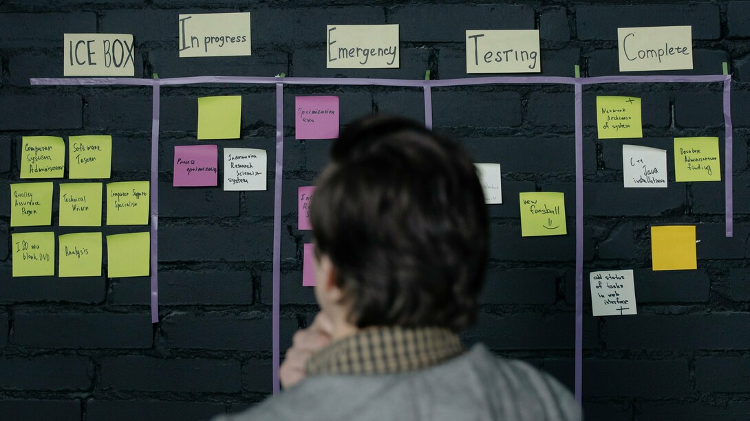 A professional reviewing a project workflow board, representing the importance of building systems that support consistent execution