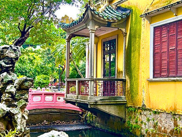Yellow-facade building connected to the garden by a pastel bridge © Alma Reyes