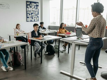 A professora orienta os alunos em sala de aula durante a atividade coletiva. O ambiente escolar deve acolher, mas também desafiar cada estudante a desenvolver responsabilidade e autonomia