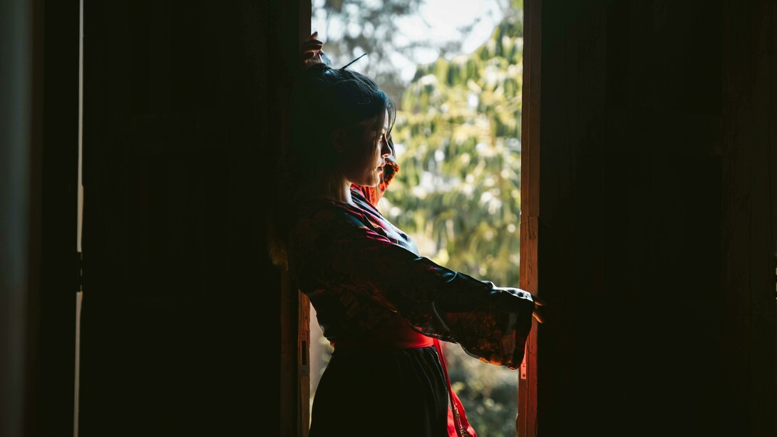 Silhouette of a woman in traditional attire by the window