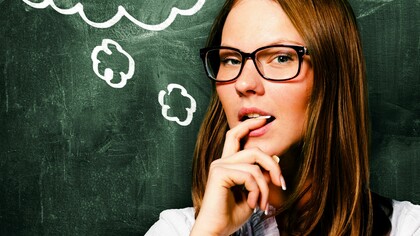 Una profesora pensativa junto a la pizarra