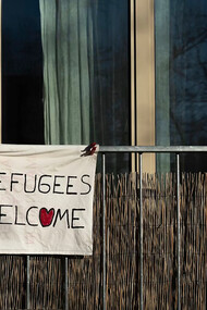 A sign reading "Refugees Welcome" displayed on a building