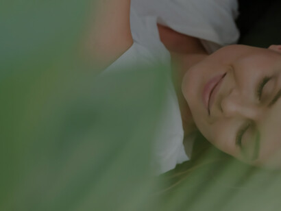 Close-up woman with closed eyes and blurred plant
