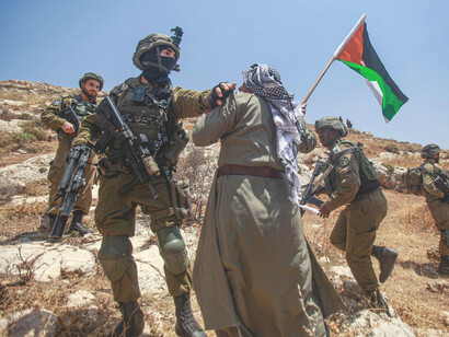 Un soldado israelí y un hombre palestino se encaran cerca de la Franja de Gaza