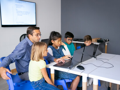 Una scena di gruppo in classe, con un insegnante e tre alunni mentre lavorano insieme al computer