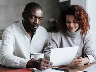 A couple thoughtfully reviewing financial documents together, representing the importance of shared responsibility in building a secure future