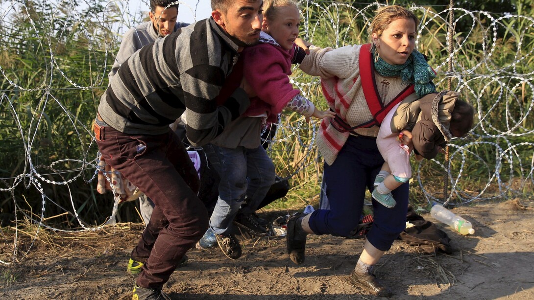 Migrantes tratan de pasar una de las alambradas levantadas en alguna frontera europea