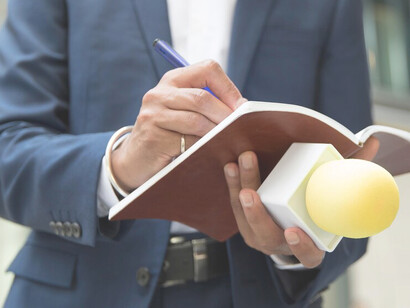 Journalist taking notes during an interview, holding a microphone