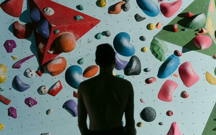 A silhouette of a man standing before a climbing wall, preparing to climb