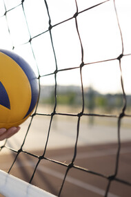 During a fast-paced rally, the ball strikes the net in a volleyball match, creating a moment of suspense as players prepare for the next move