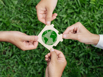 Businesses, corporations, and communities must work together to achieve environmental sustainability, symbolized by holding a paper globe in their hands