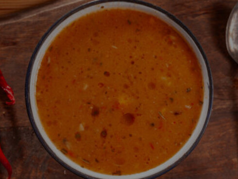 A woman enjoys tarhana soup served on a rustic wooden tray
