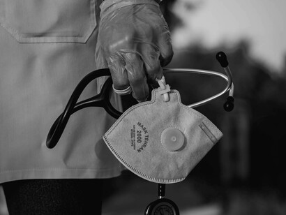 A doctor holds a stethoscope and mask during COVID
