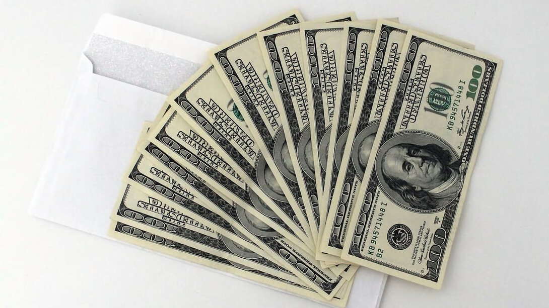 Dollars are placed beside a white envelope