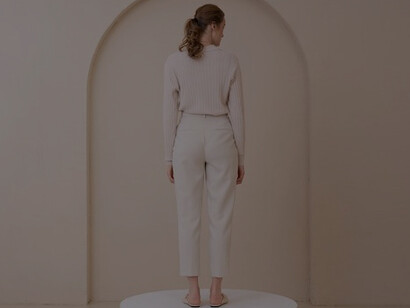 A woman, clad in simple, minimalist attire, exudes elegance against a backdrop of clean, minimalist design