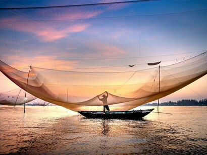 A fishermen casting their nets at twilight, reflecting the simple dignity of lives shaped by the ocean