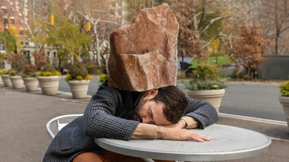 Uomo addormentato su un tavolo da esterno con una grande roccia sulla testa: "Percepisci il peso della giornata sulle spalle, contratte... Il sistema nervoso parasimpatico ti porta in modalità “protezione”: spegne tutto per permetterti di riposare"