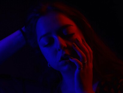 A solitary figure illuminated by contrasting colours in the dark, symbolising the emotional isolation that often comes with anxiety