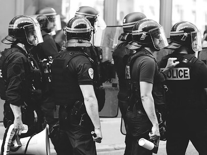 Grayscale photograph of police officers in full armor patrolling the streets