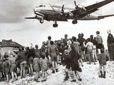 Pendant le pont aérien de Berlin en 1948, des avions américains, britanniques et français ont acheminé de la nourriture et d'autres marchandises à Berlin, qui était assiégée par les forces soviétiques. Sur cette photo, des enfants allemands se tiennent sur une colline et regardent passer un avion américain