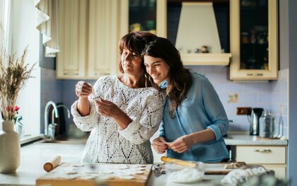 A woman in a blue long-sleeve shirt cooking in the kitchen with her mother
