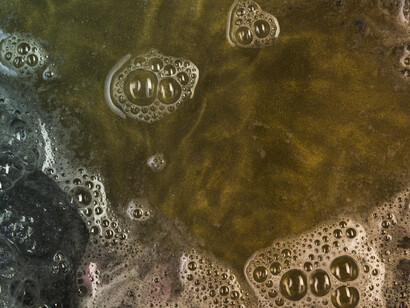 Thick, swirling liquid with trapped bubbles reveals the dense, contaminated texture of industrial waste or oil residue