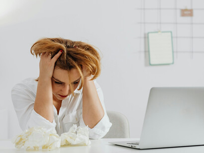 A short-haired woman leans on a table, conveying information overload and mental fatigue in modern life