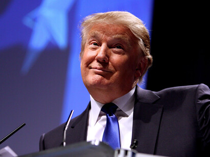 Donald Trump at a press conference, smiling confidently