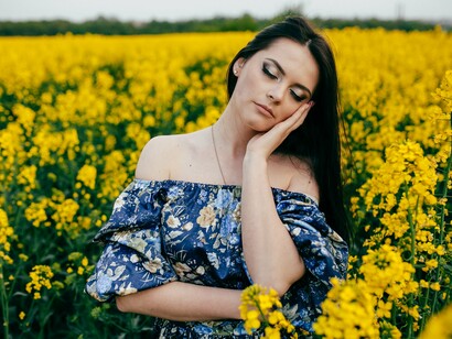 A calm woman standing among yellow flowers, representing the peace that follows emotional reconstruction