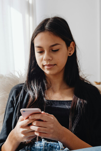 Using her mobile phone, a woman in a black long-sleeved outfit binge-watches short vertical drama episodes designed for smartphone viewin
