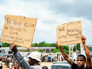 Citizens holding protest signs during a public demonstration, reflecting public dissatisfaction with political and social conditions