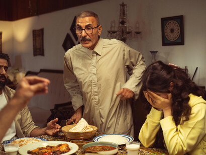A family sits in silence during a tense disagreement around the dinner table indoors