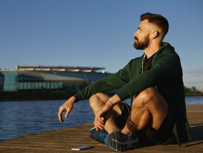 A man relaxing by the water with his phone set aside, reflecting the importance of creating space for reflection