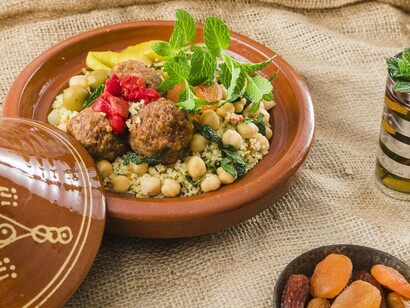 A traditional Moroccan tagine served with couscous, chickpeas, and fresh herbs