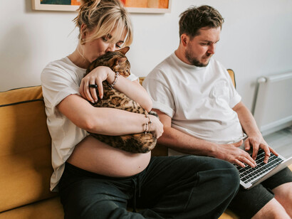 Pareja embarazada en el sillón con su gato. A pesar de las dificultades, el vínculo formado con los gatos es fuerte