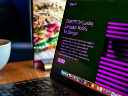 A sleek MacBook sits open, its screen displaying the homepage of ChatGPT, an AI language model designed to enhance communication and deliver insightful information to user