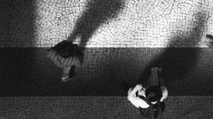 Dois homens caminham sem rumo pela cidade