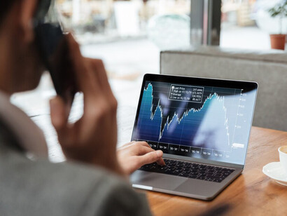 A businessman seated at a café, focused on analyzing the stock market data on his laptop