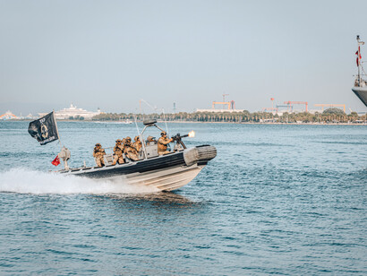 Lancha militar táctica navegando a gran velocidad por el agua, con soldados a bordo y armamento listo durante una exhibición o patrulla naval