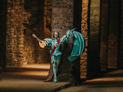 A figura performática e seu instrumento compõem uma cena suspensa entre o espetáculo e a melancolia. A imagem dialoga com o percurso de Afonso, cujas recordações, paixões e despedidas revelam a beleza da vida justamente quando ele se aproxima de seus limites