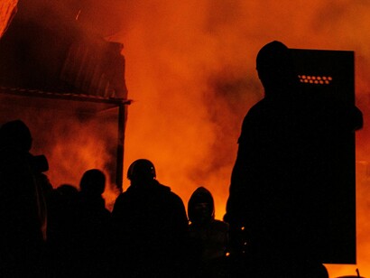 Protesters amid raging fires at night, representing the escalation from dissatisfaction to destruction