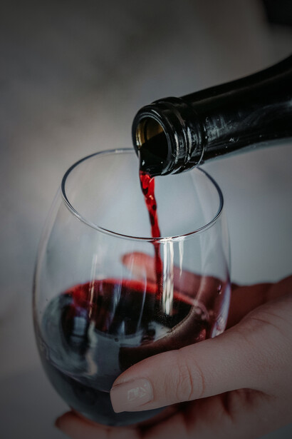 A person pouring wine from a decanter into a wine glass